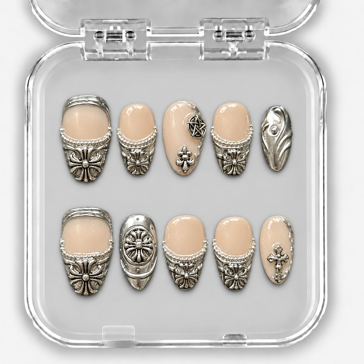 Set de dix press-on nails courts nude et argent, avec ornements métalliques dans leur boîte.