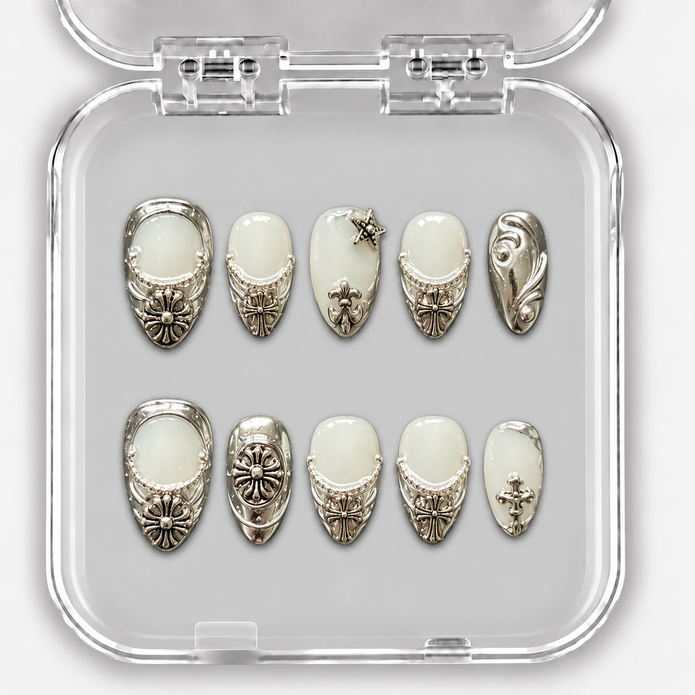 Set de dix press-on nails courts blanc laiteux et argent, avec ornements métalliques dans leur boîte.