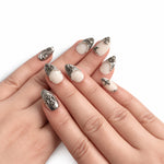 Blanc & Argent — Court : press-on nails portés, vue des mains, ornements argentés sur fond blanc.