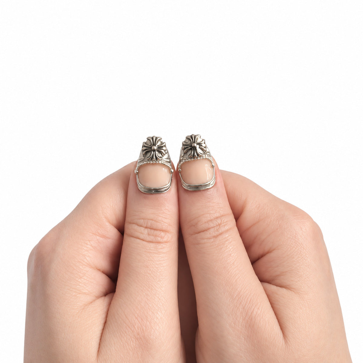 Nude & Argent — Court : press-on nails portés, détail des pouces, ornements argentés sur fond blanc.