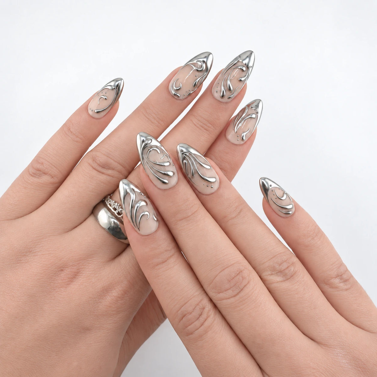LIQUID SILVER porté sur les deux mains croisées : huit ongles amande nude avec french et arabesques chromées argentées.