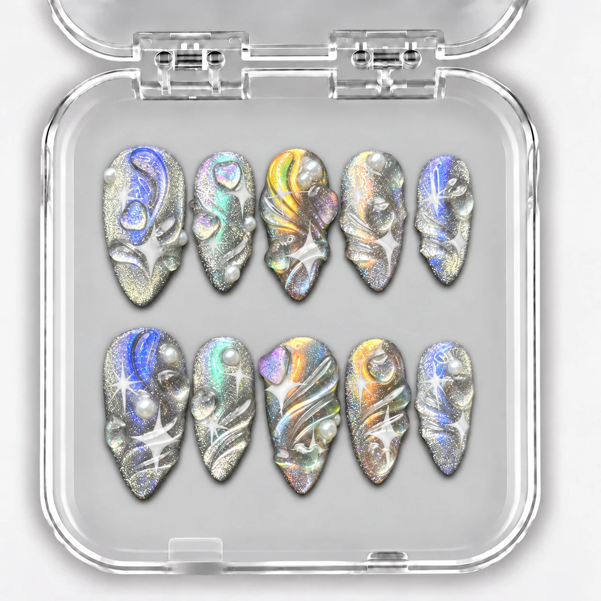 Ongles press-on NELI holographiques avec étoiles blanches, perles et reliefs argentés, dans une boîte transparente.